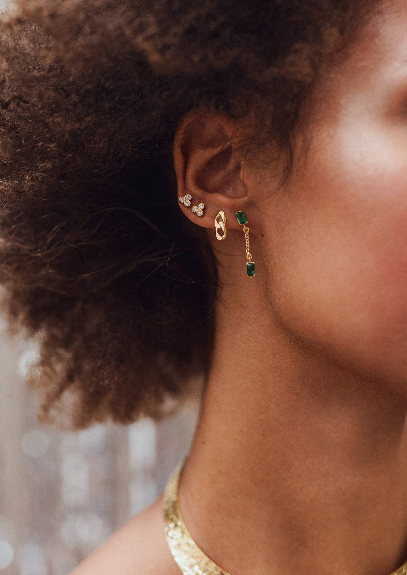 Model wearing a stack of fine gold and emerald earrings — Auric Jewels editorial