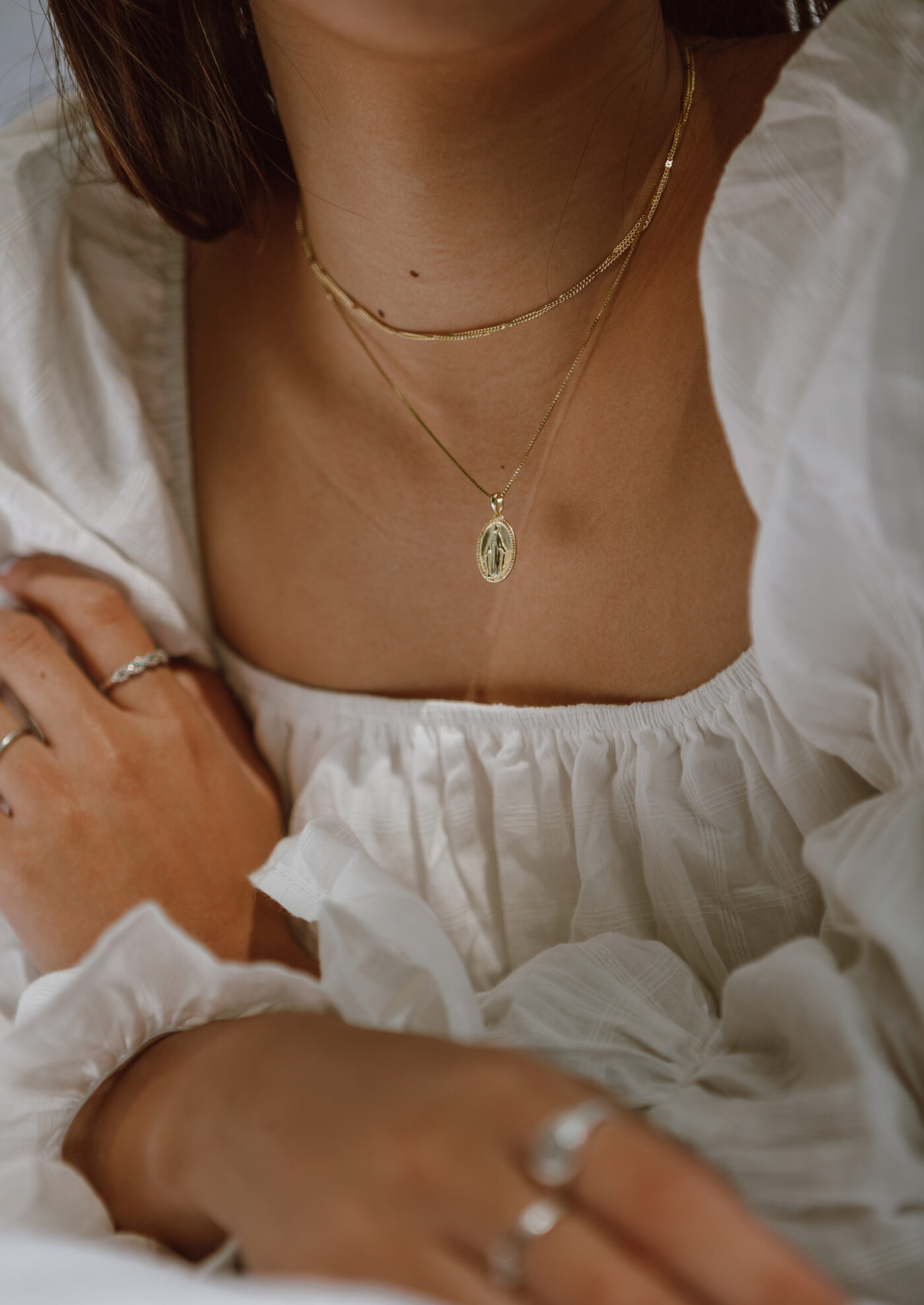 Layered gold chain with engraved pendant on ivory dress